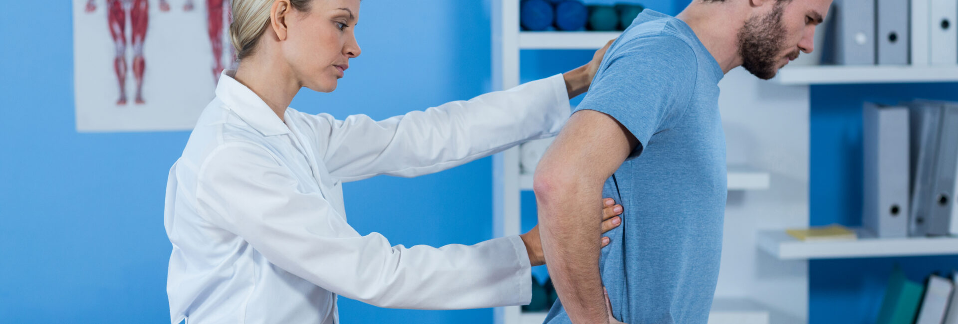 Physiotherapist examining mans back in clinic
