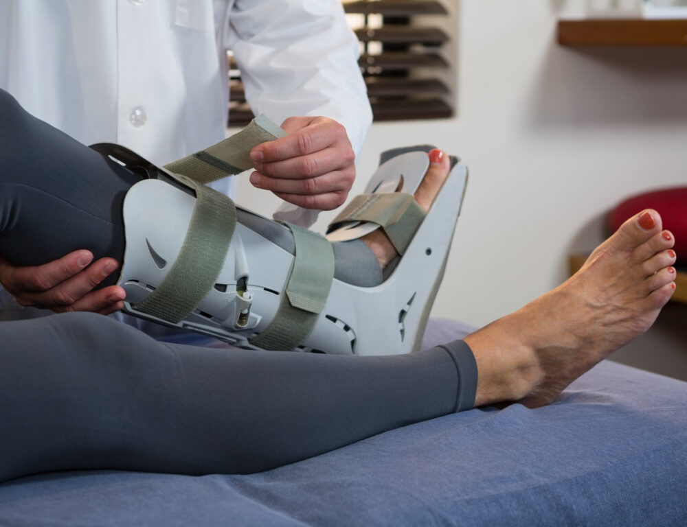 Physiotherapist tying leg pad in clinic